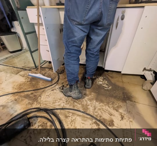 אינסטלטור עובד מתחת לכיור עם כלים וצינורות